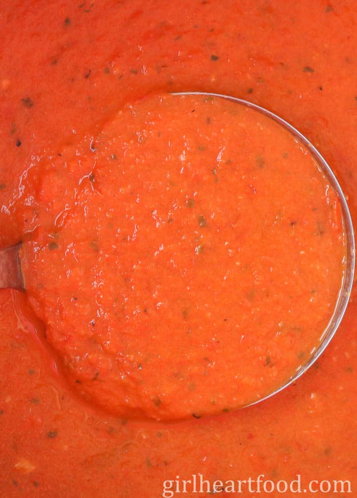 Close-up of a ladle scooping up tomato soup.