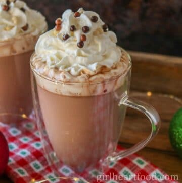 Mug of orange hot chocolate with whipped cream and candy on top.