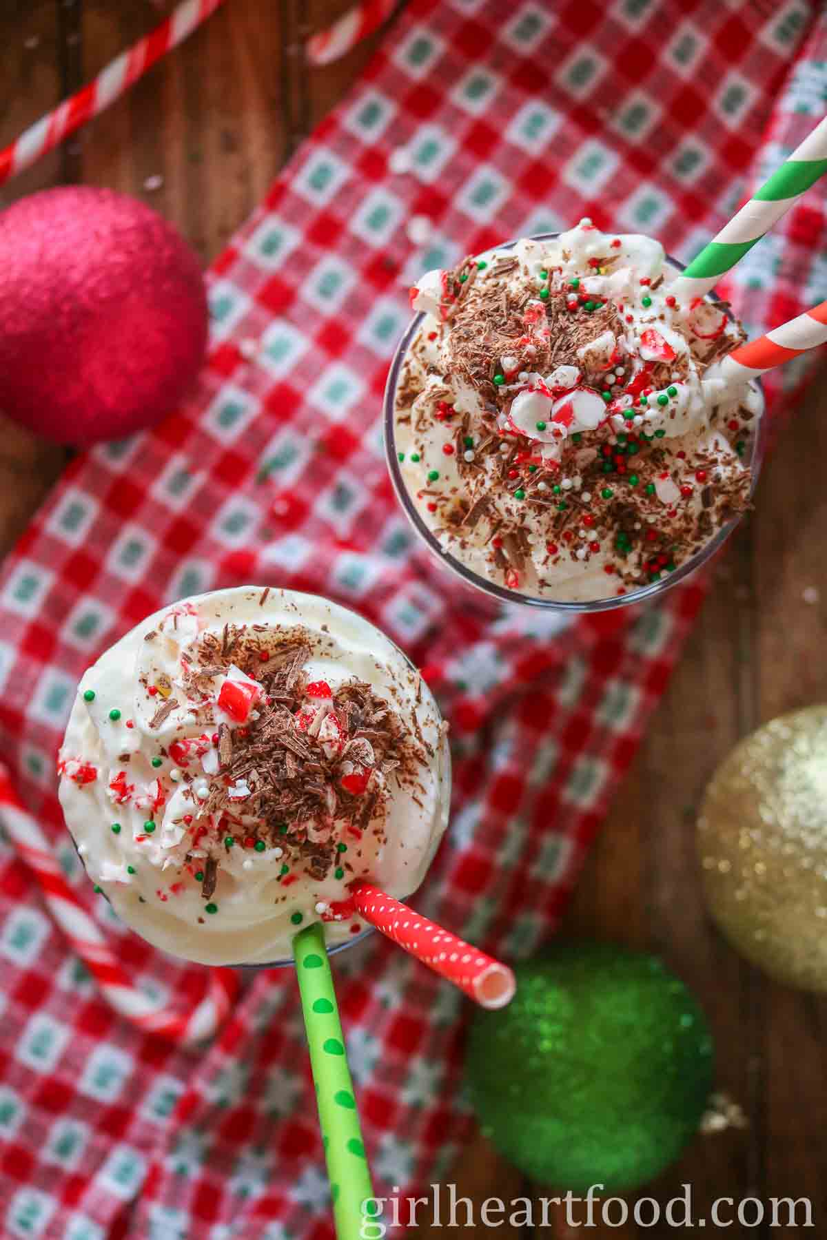 Overhead shot of two glasses of candy cane milkshake with whipped cream and toppings.
