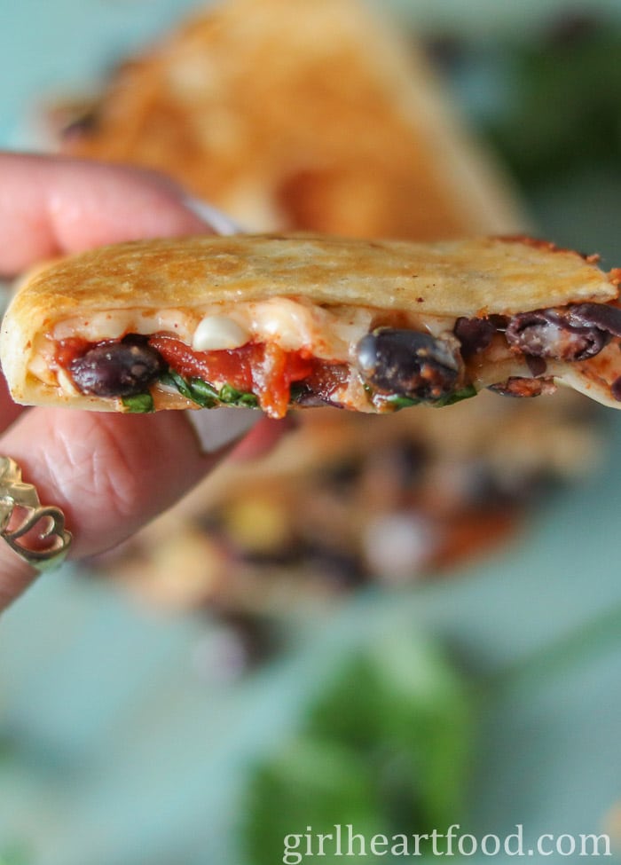 Hand holding a black bean quesadilla.