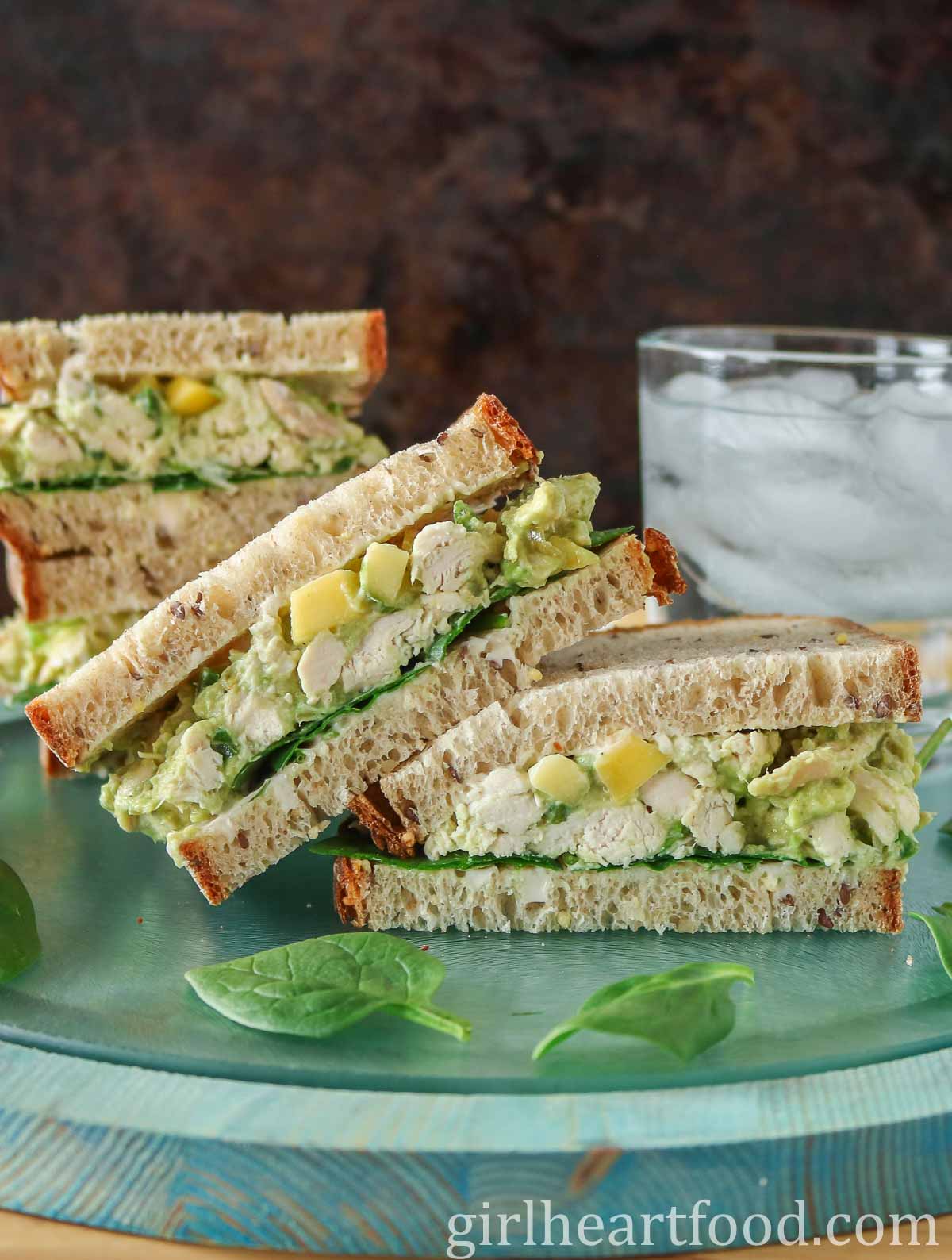 Two halves of a chicken and avocado salad sandwich, one half resting on the other half.