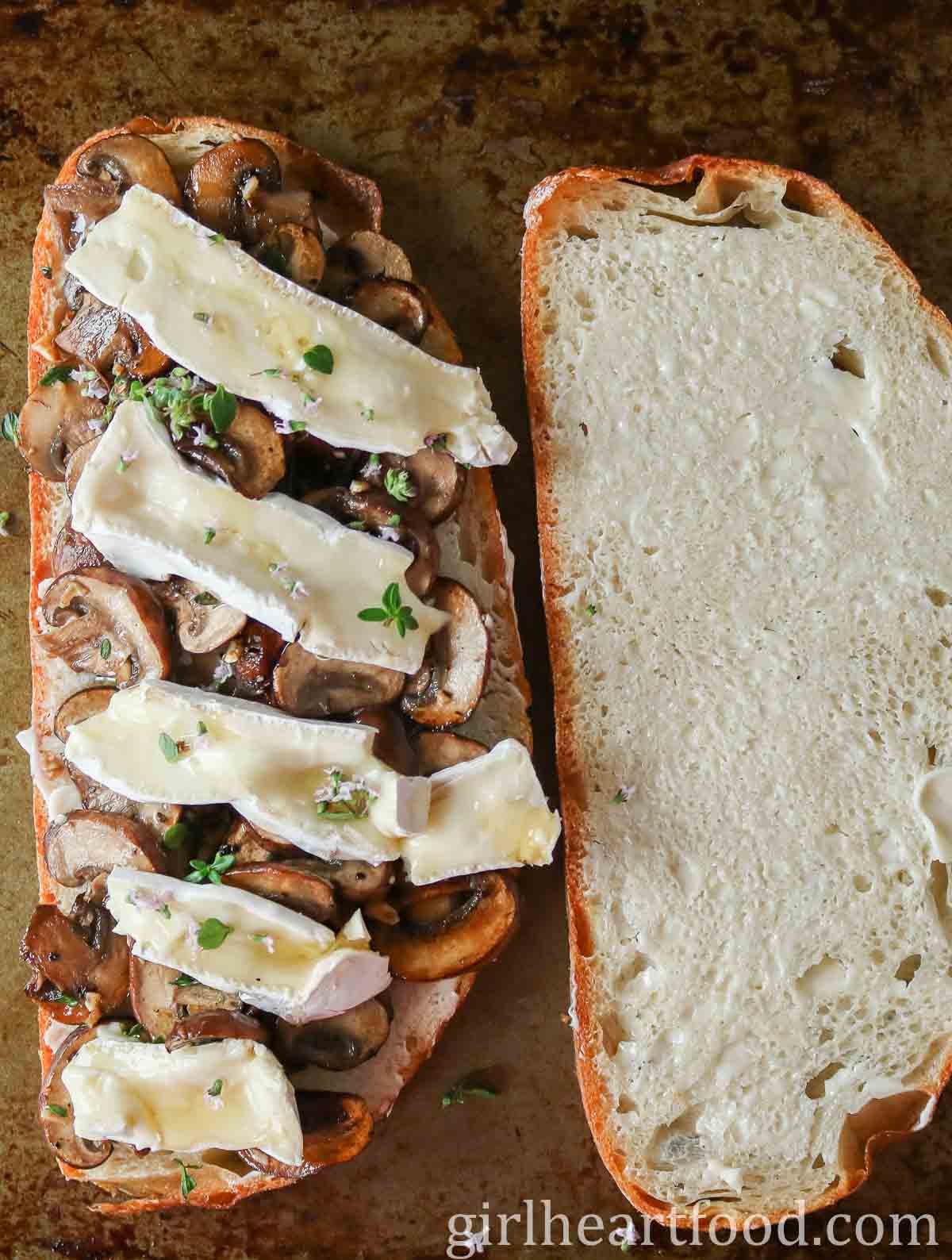 Two slices of bread: one with mushrooms, Brie, thyme & honey and the other with butter.