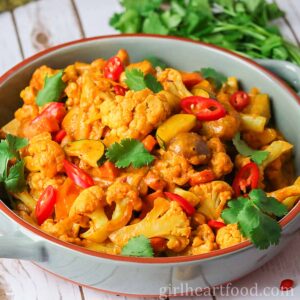 Vegetable korma in a dish with some fresh cilantro behind it.