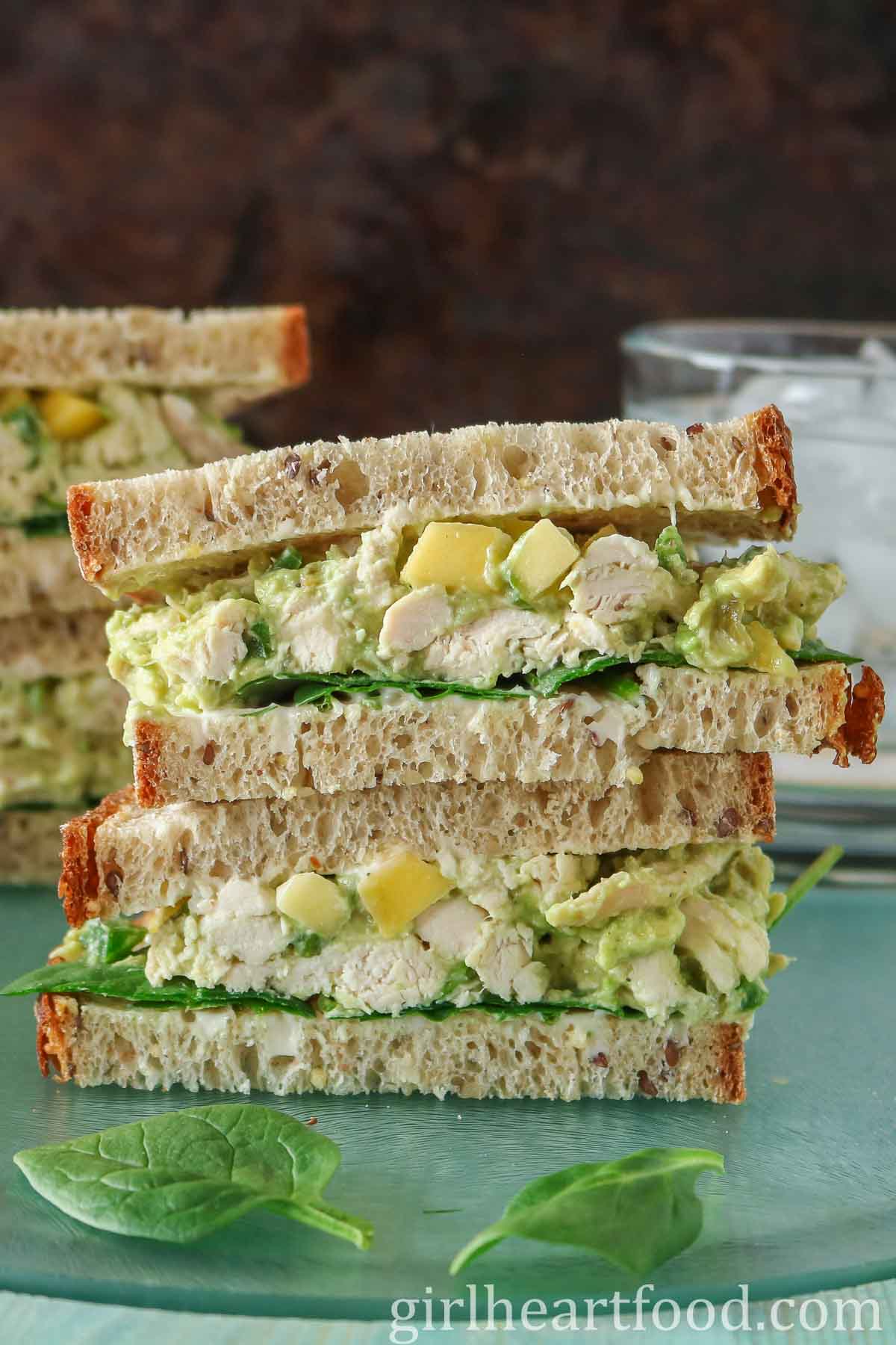 Stack of two halves of a chicken avocado sandwich.