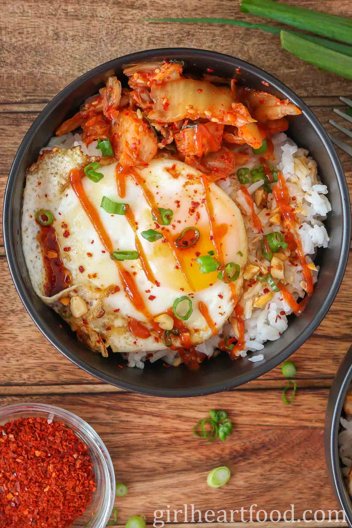 Fried egg and rice bowl drizzled with hot sauce.