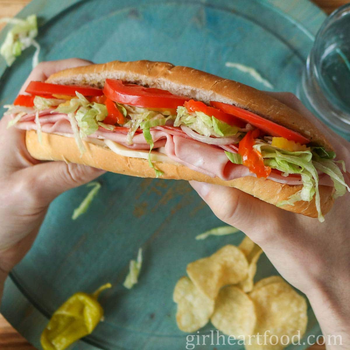Two hands holding an Italian cold cut sub sandwich.