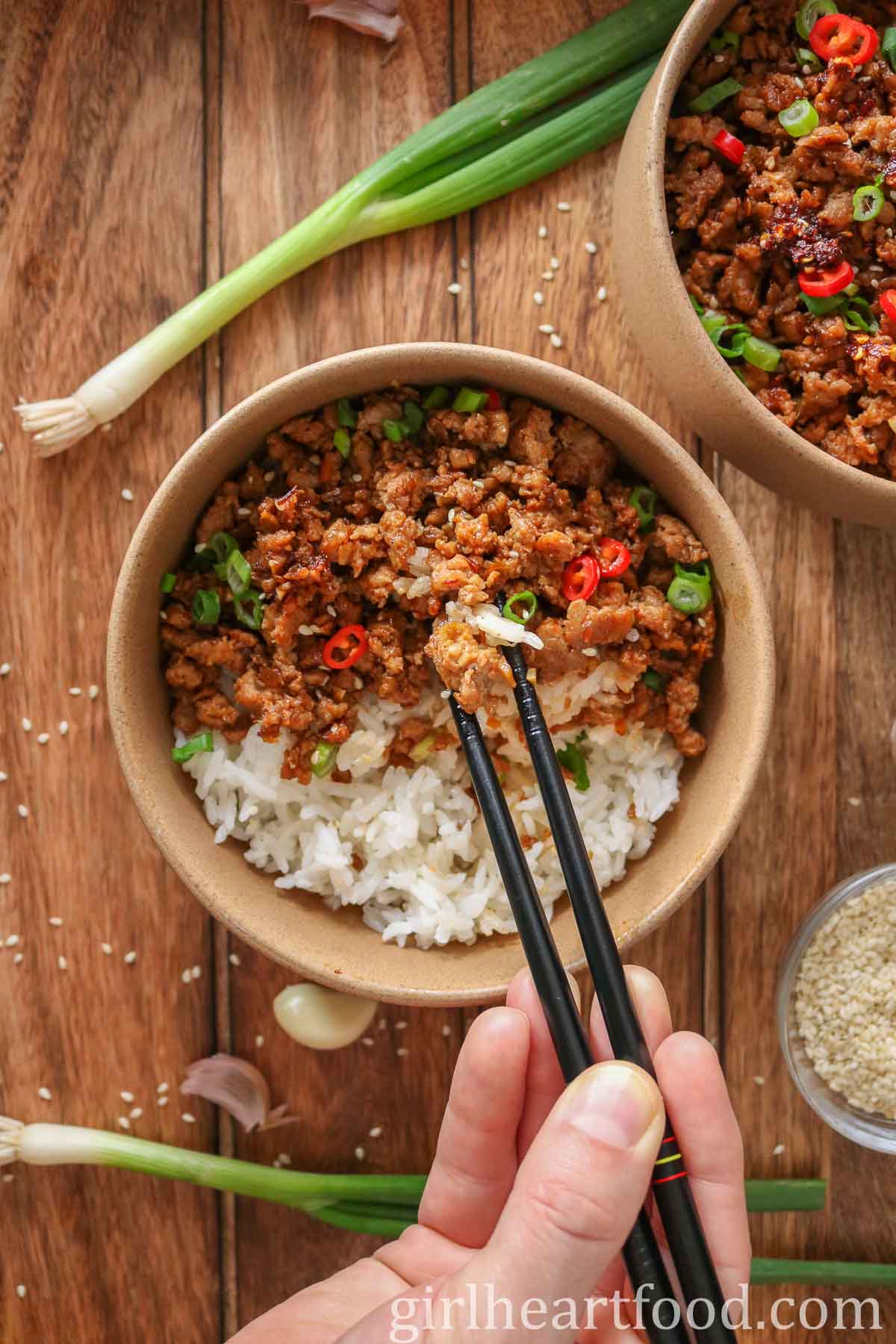 Hand holding chopsticks, picking up food from a turkey rice bowl.