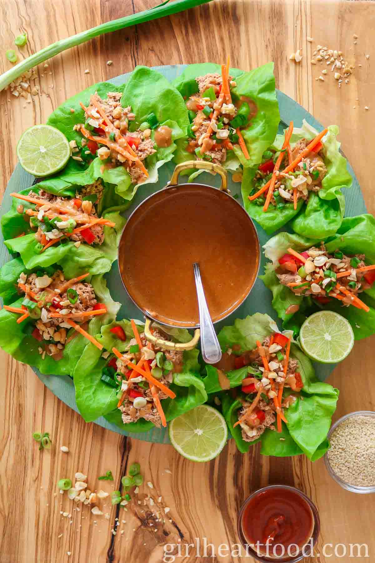 Platter of tuna lettuce wraps with a small pot of peanut sauce in the centre.