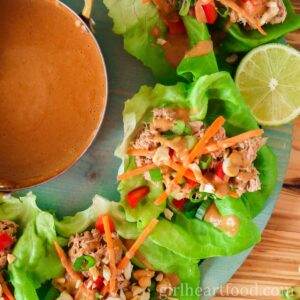 Tuna lettuce wraps with peanut sauce next to a pot of sauce and half a lime.