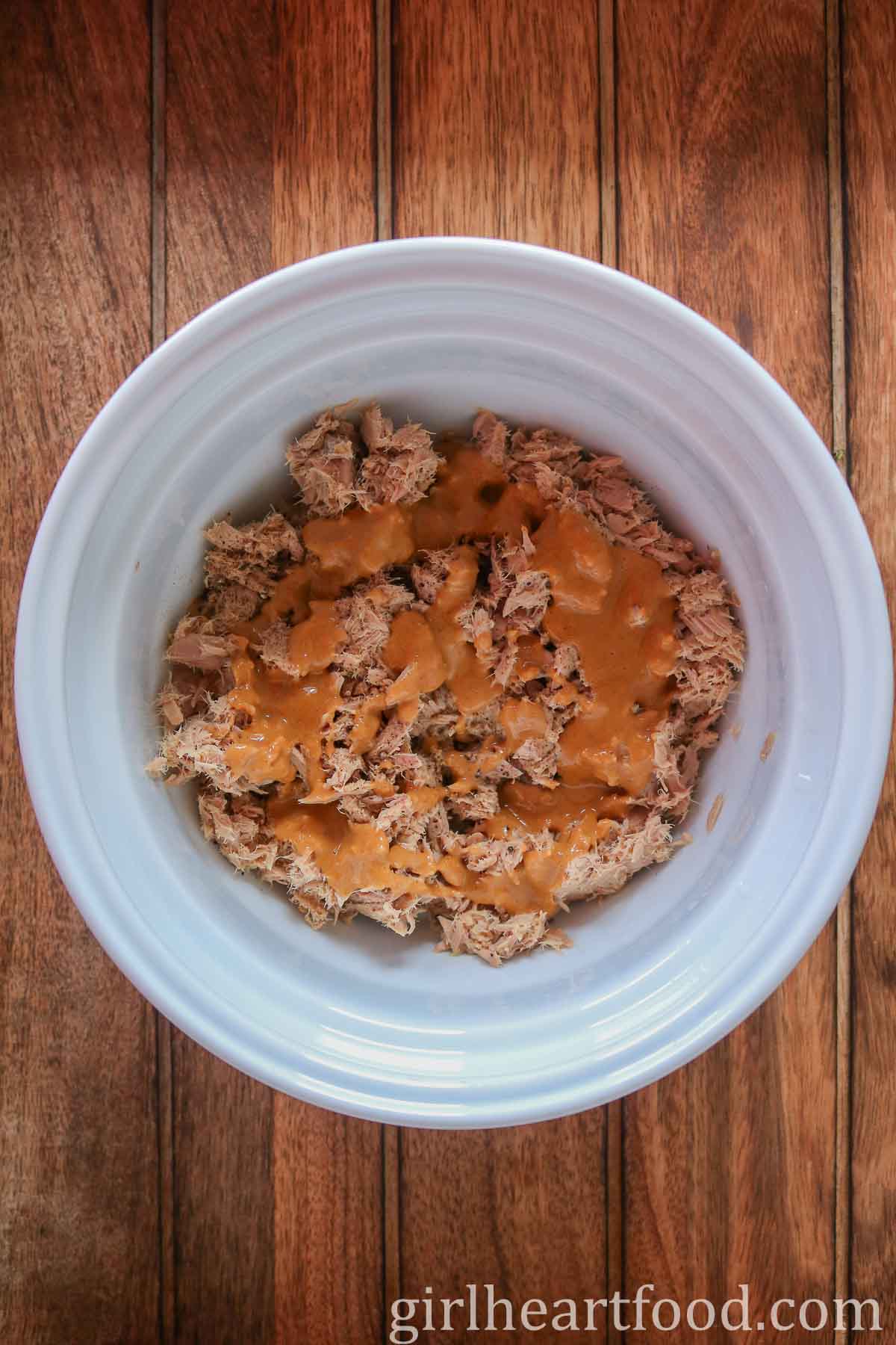 Canned tuna with peanut sauce in a white bowl.