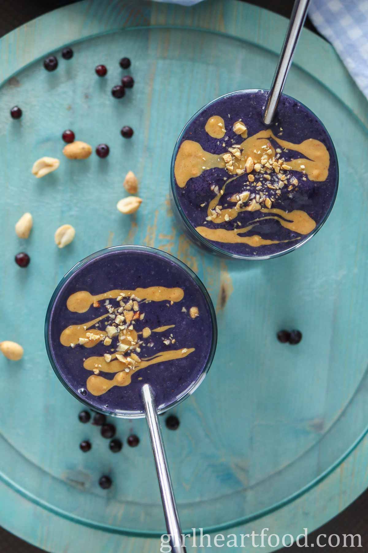 Overhead shot of two glasses of blueberry peanut butter smoothie.