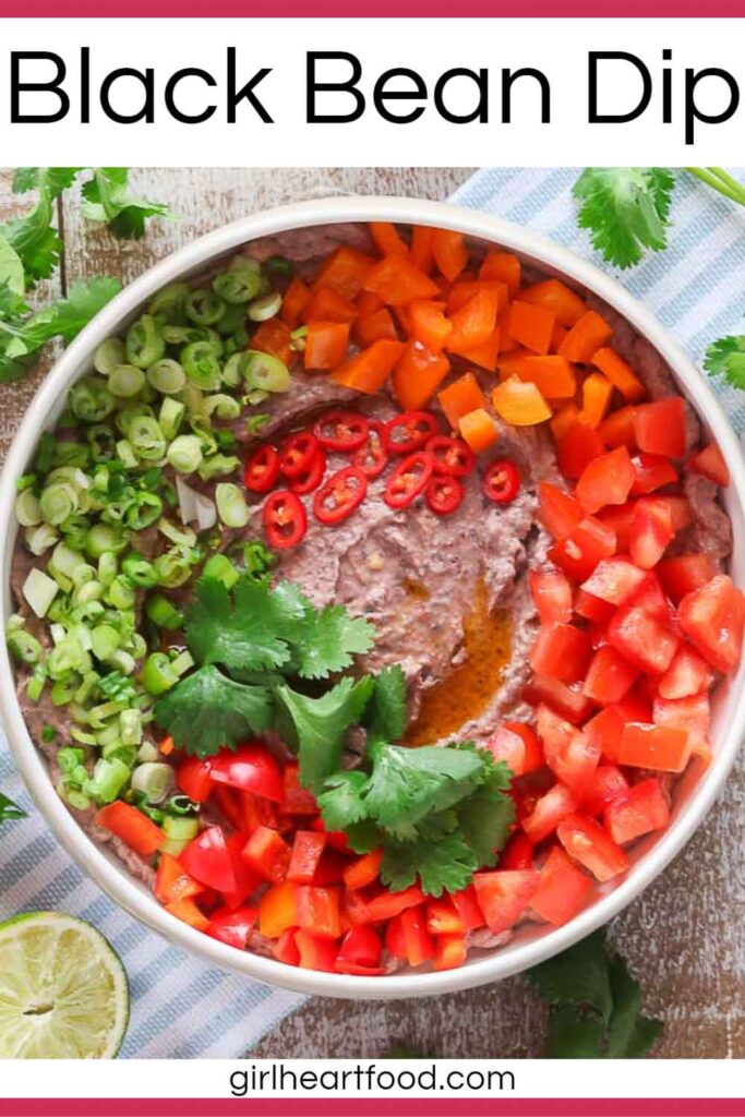 Bowl of black bean dip garnished with toppings.