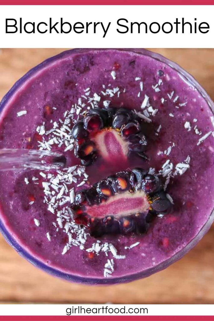 Overhead shot of a glass of blackberry smoothie topped with a cut blackberry and coconut.