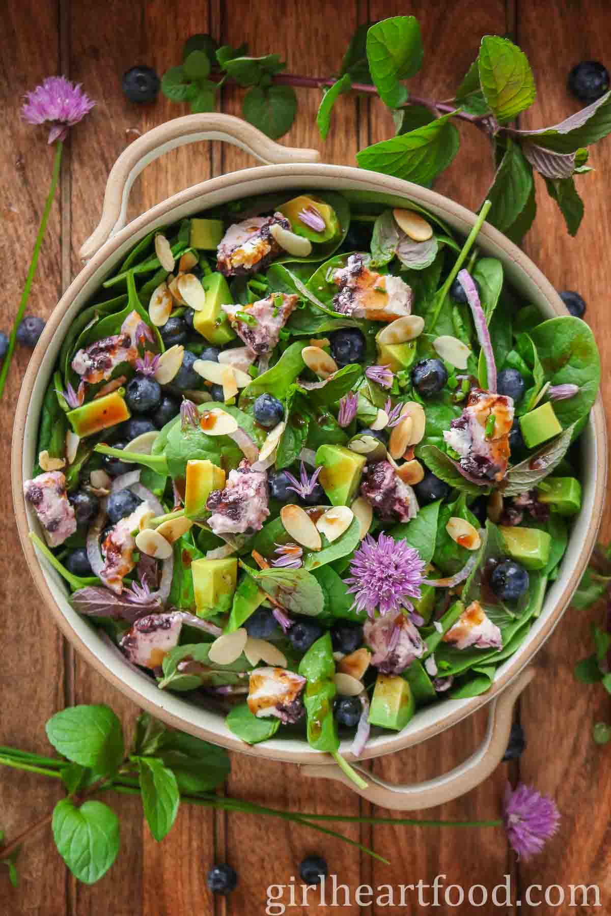 Dish of blueberry spinach salad drizzled with vinaigrette.