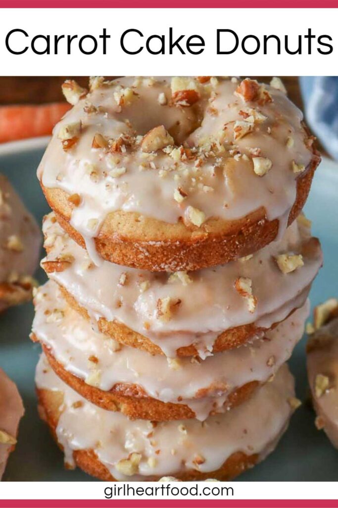 Stack of carrot cake donuts with icing sugar glaze and chopped nuts.
