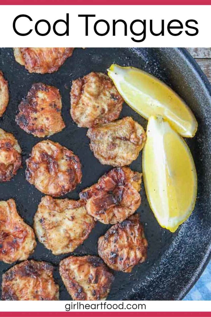 Pan-fried cod tongues and two lemon wedges in a cast-iron skillet.