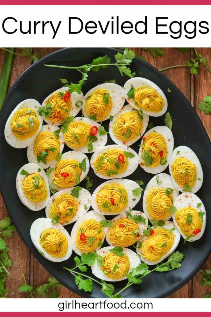 Curried deviled eggs on a black platter.