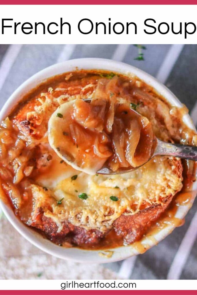 Spoonful of French onion soup held above a bowl of it.