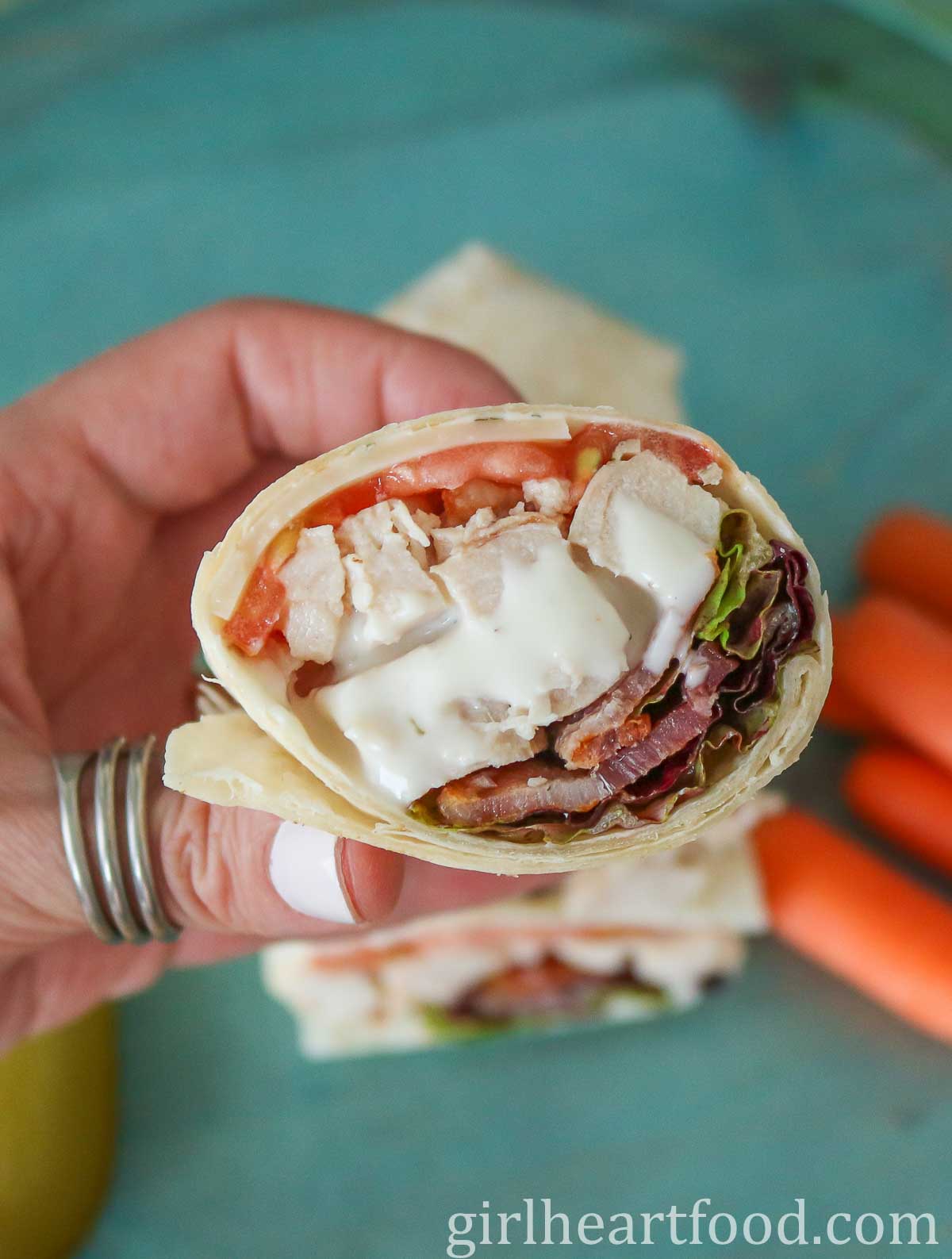 Hand holding a turkey bacon wrap with ranch dressing.