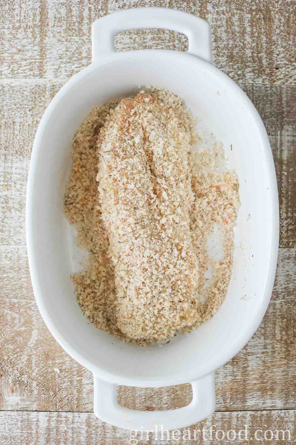 Fillet of cod with panko bread crumbs in a white dish.