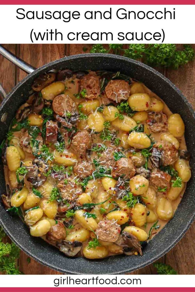 Sausage, gnocchi, mushrooms, spinach and cream sauce in a frying pan.