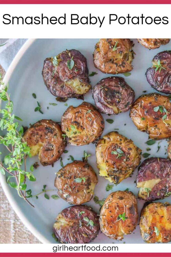 Smashed roasted baby potatoes with herbs on a blue plate.