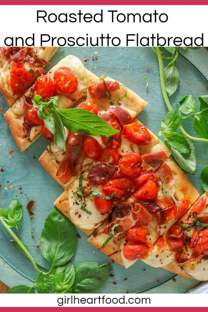 Tomato and prosciutto flatbread pizza, cut into pieces, with basil on either side of it.