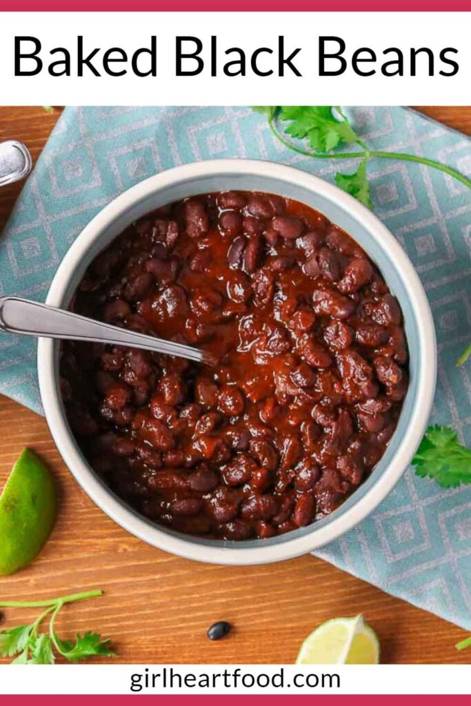 Bowl of baked black beans next to some lime and cilantro.