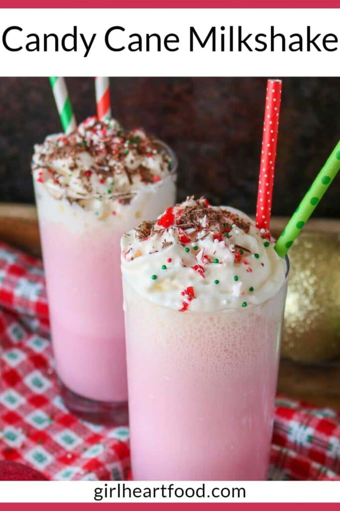 Two glasses of pink candy cane milkshake with whipped cream and toppings.