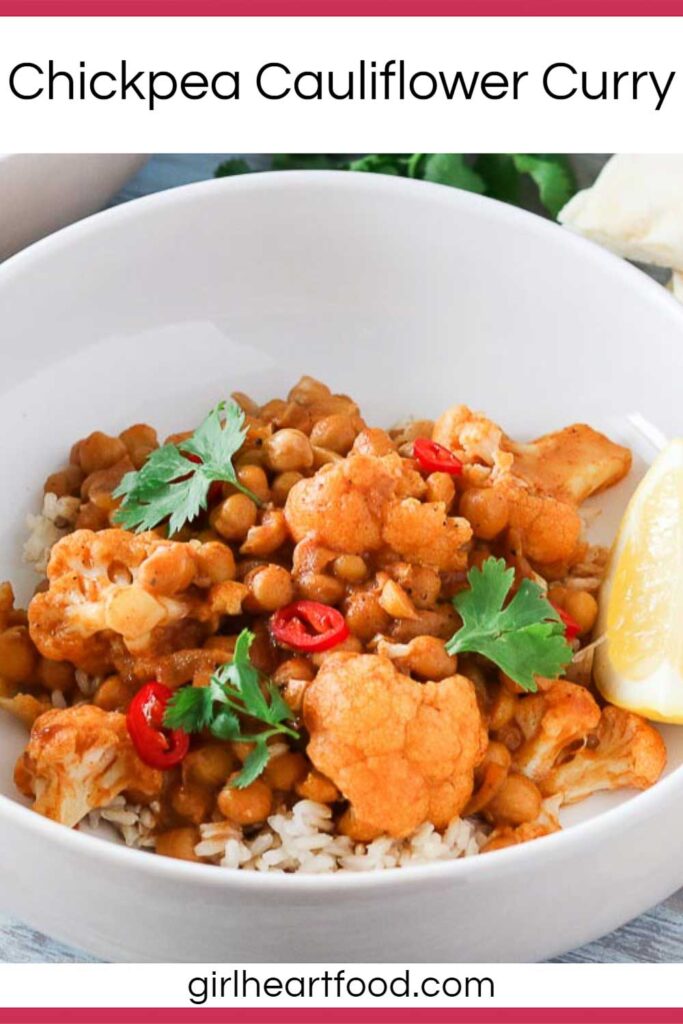 Bowl of chickpea cauliflower curry and rice garnished with chili pepper, cilantro and lemon.