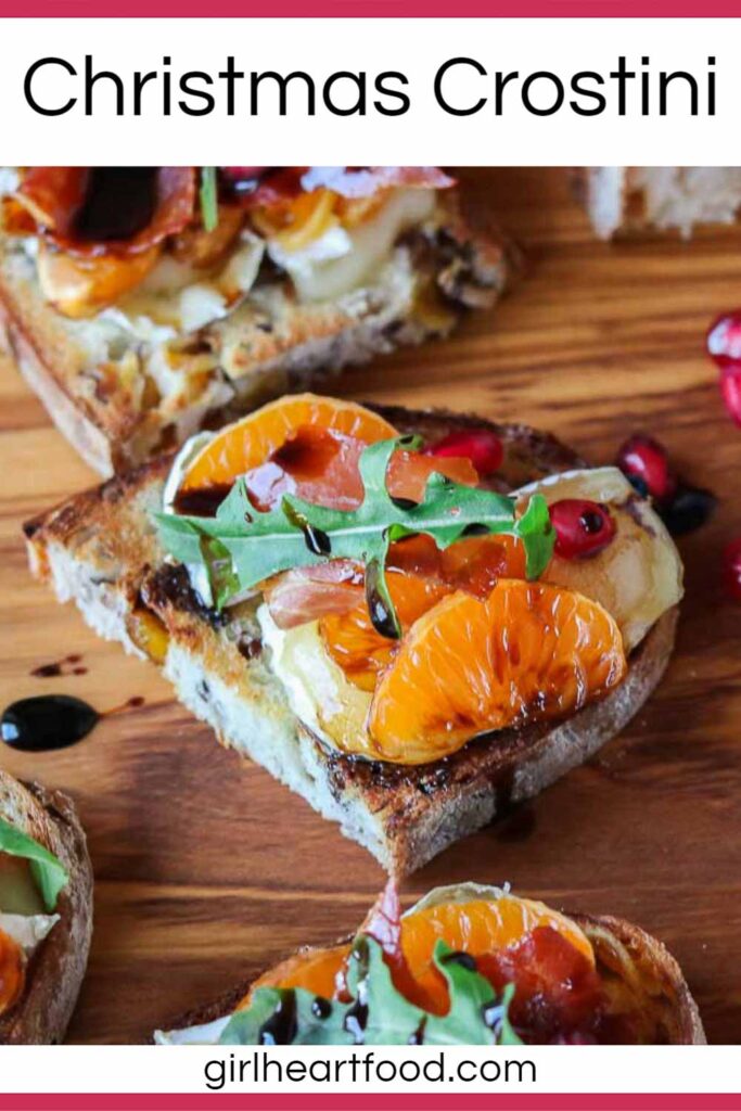 Close-up of a crostino with clementine, Brie, prosciutto, arugula and balsamic on a serving board.