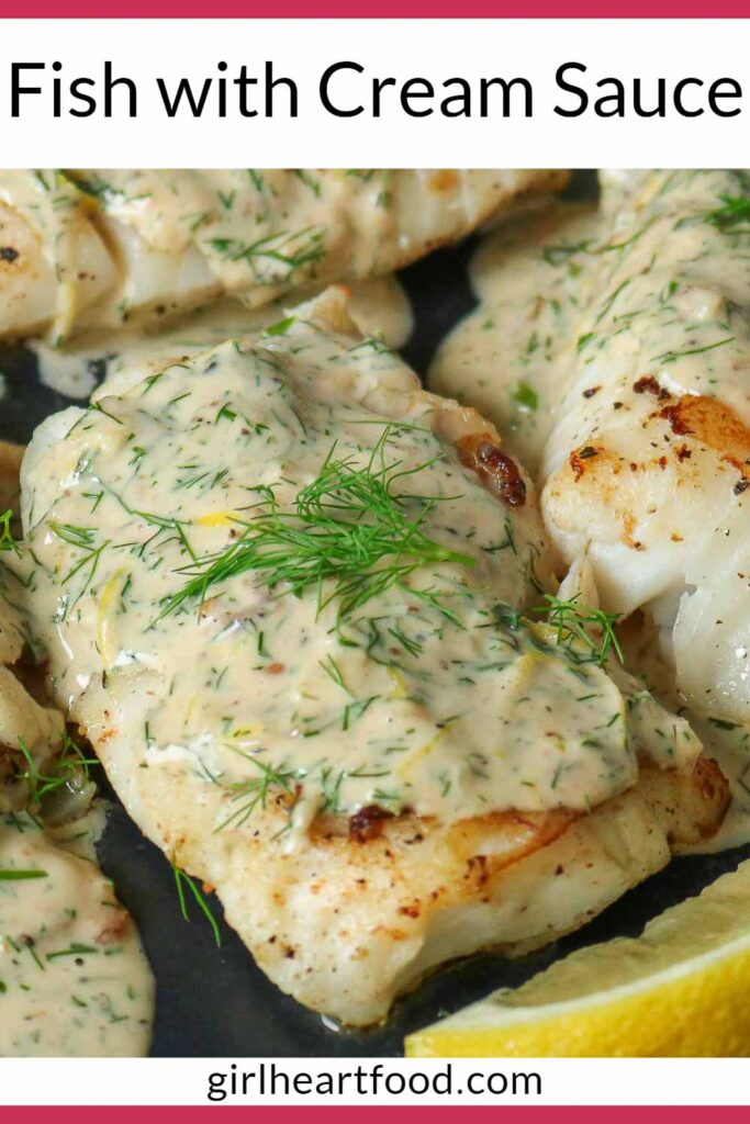 Close-up of a cod fillet covered in a creamy dill sauce next to a lemon wedge.