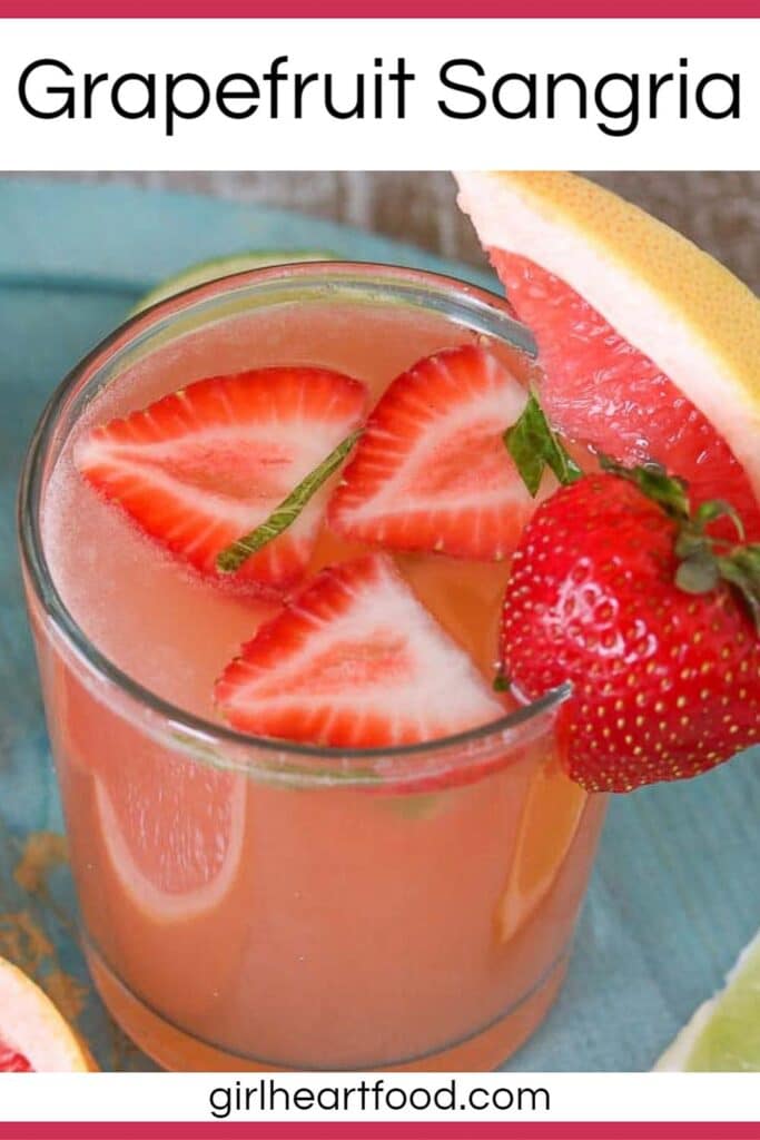 Close-up of a glass of grapefruit rosé sangria garnished with strawberry and grapefruit.
