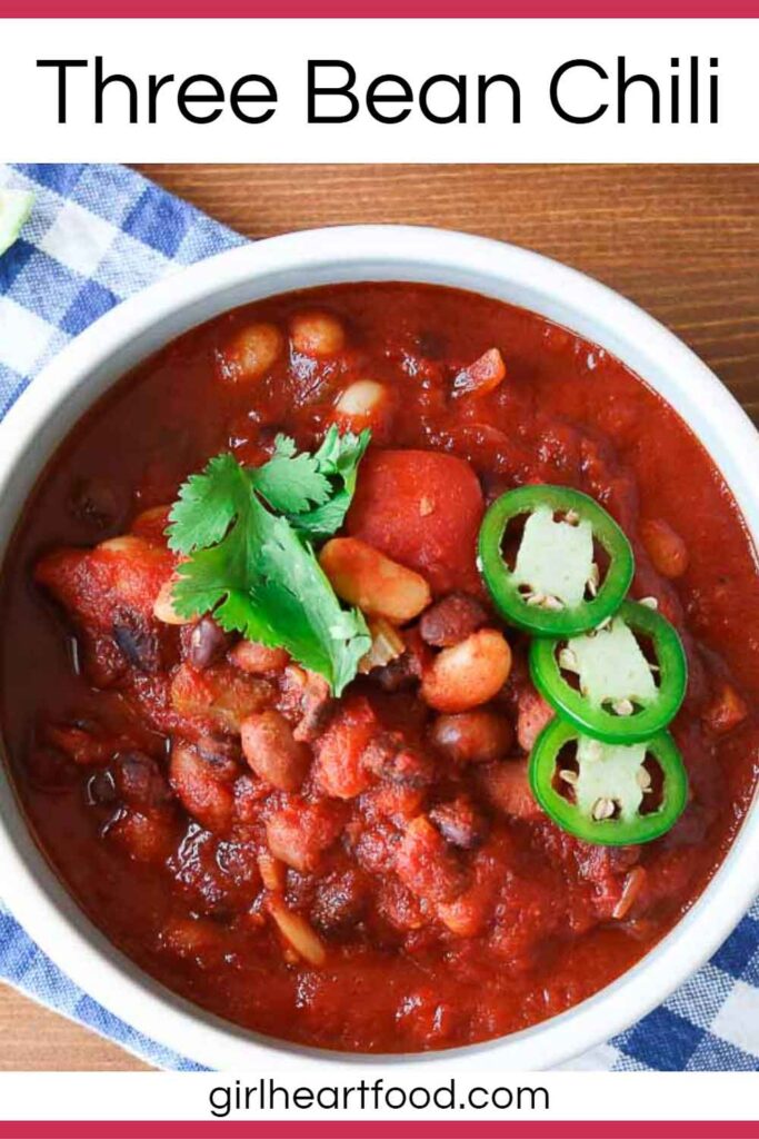 Bowl of three bean chili garnished with toppings.