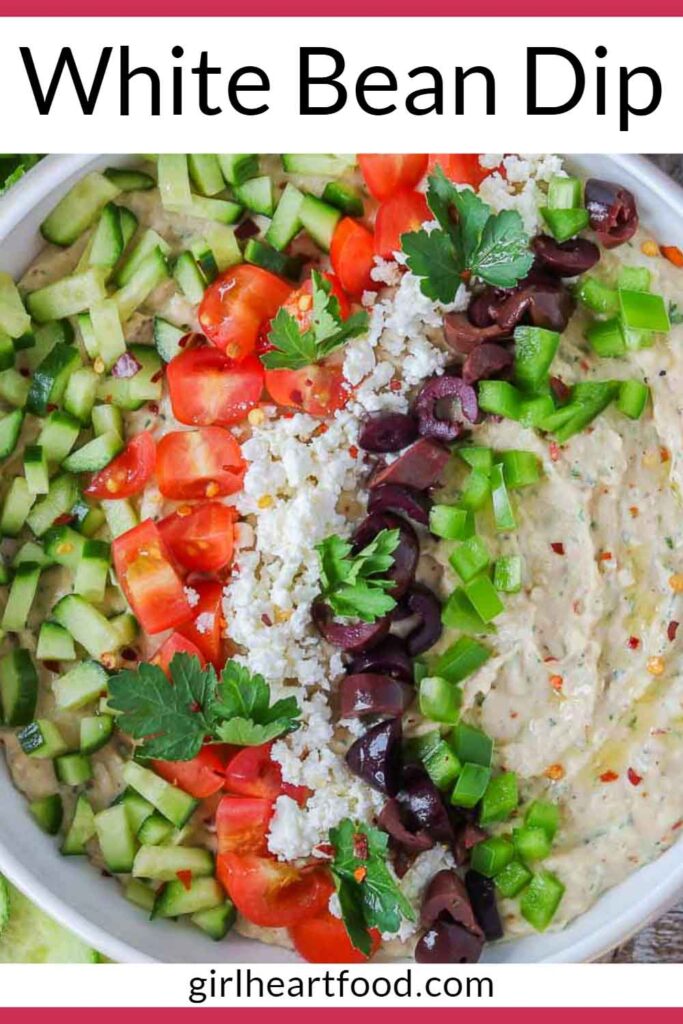 Bowl of Mediterranean white bean dip garnished with toppings.