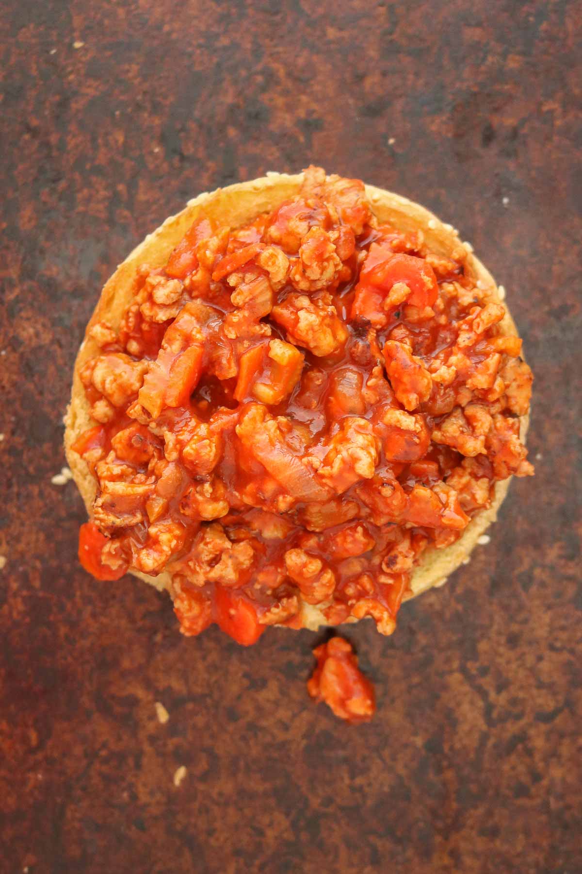 Sloppy joe mixture on a bun before the top bun is place over top.