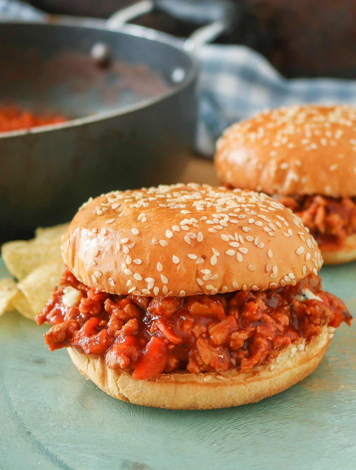 Buffalo chicken sloppy joe sitting in front of another sloppy joe and a pan.