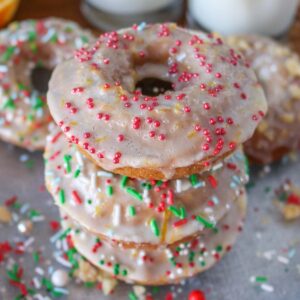 Stack of three glazed gingerbread donuts with sprinkles.