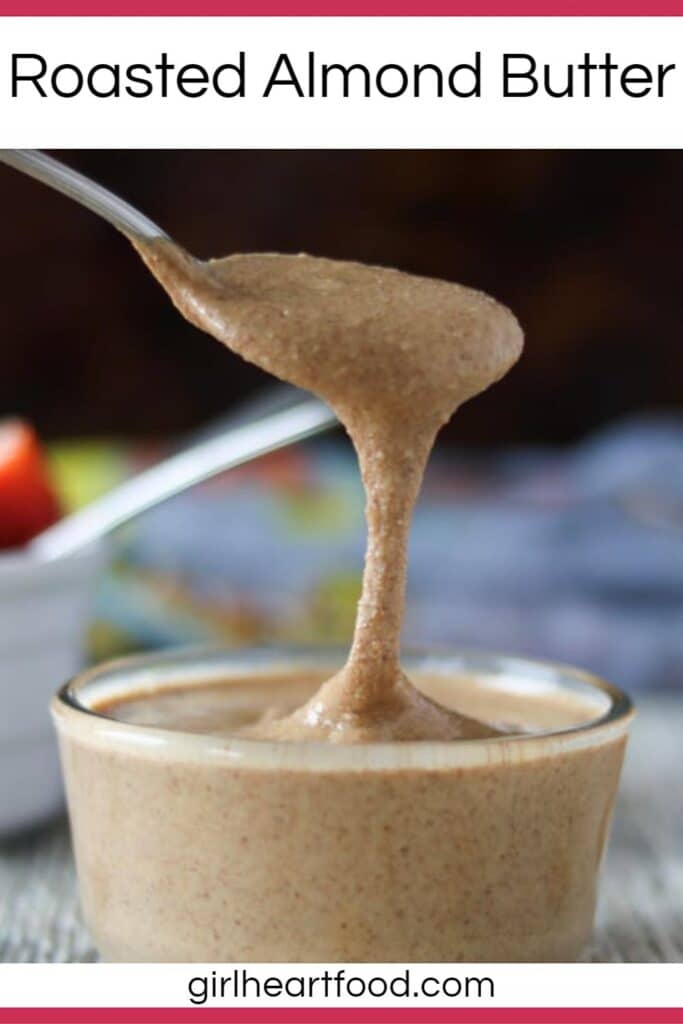 Spoonful of roasted almond butter, dripping into a jar underneath it.