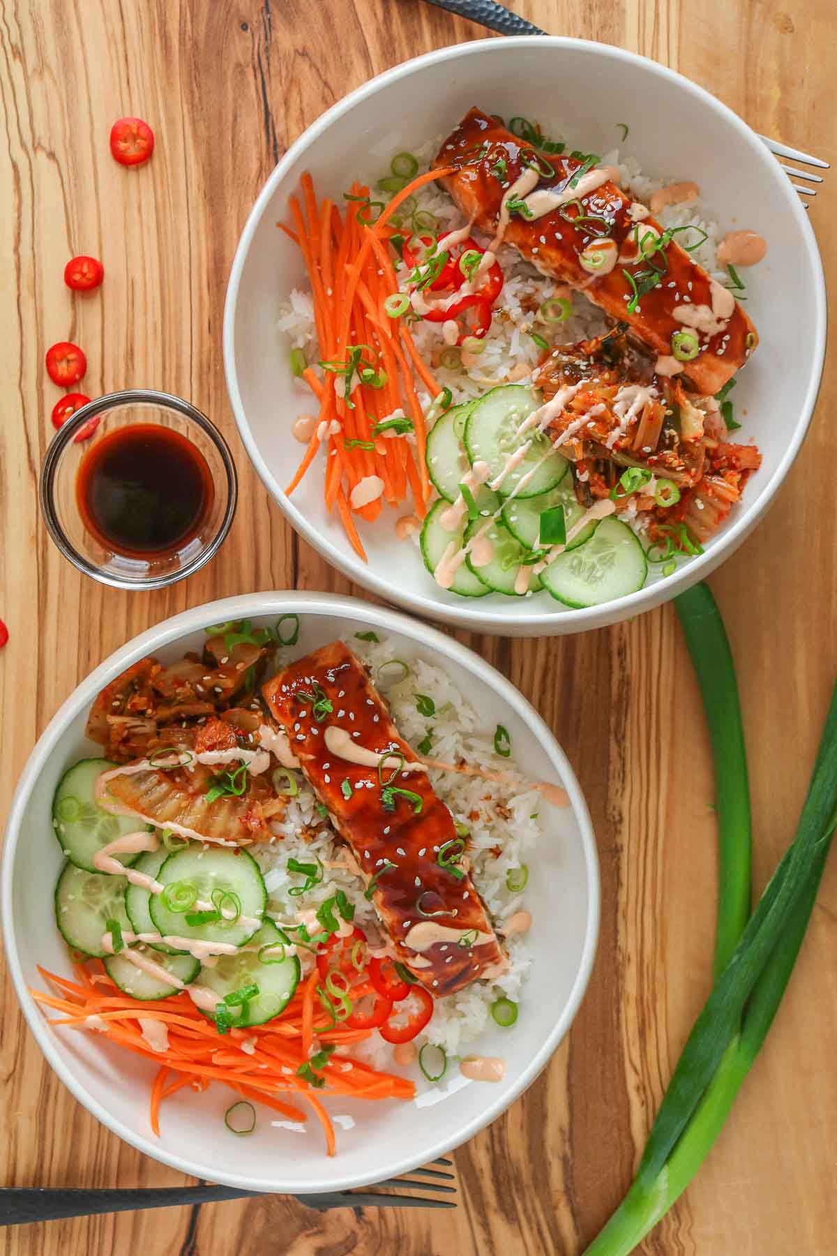 Two salmon rice bowls, each drizzled with spicy mayo.