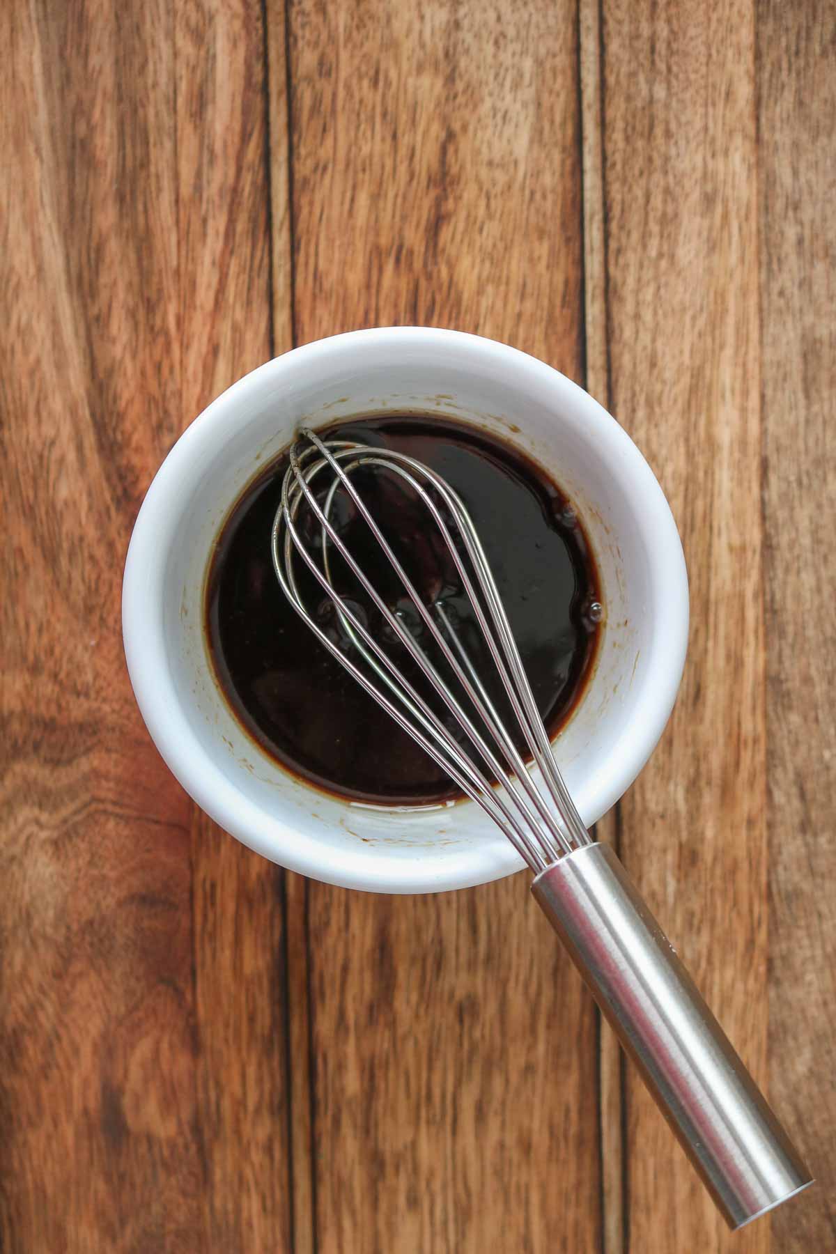 Small bowl of a soy sauce mixture with a whisk in it.