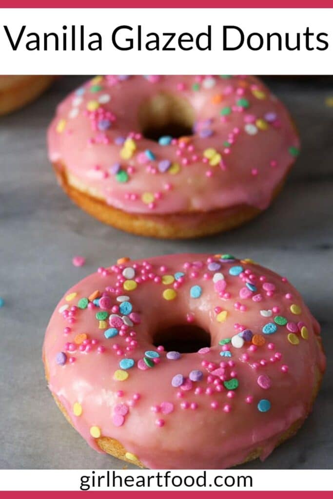 Pink vanilla glazed donuts with colourful sprinkles on a marble board.