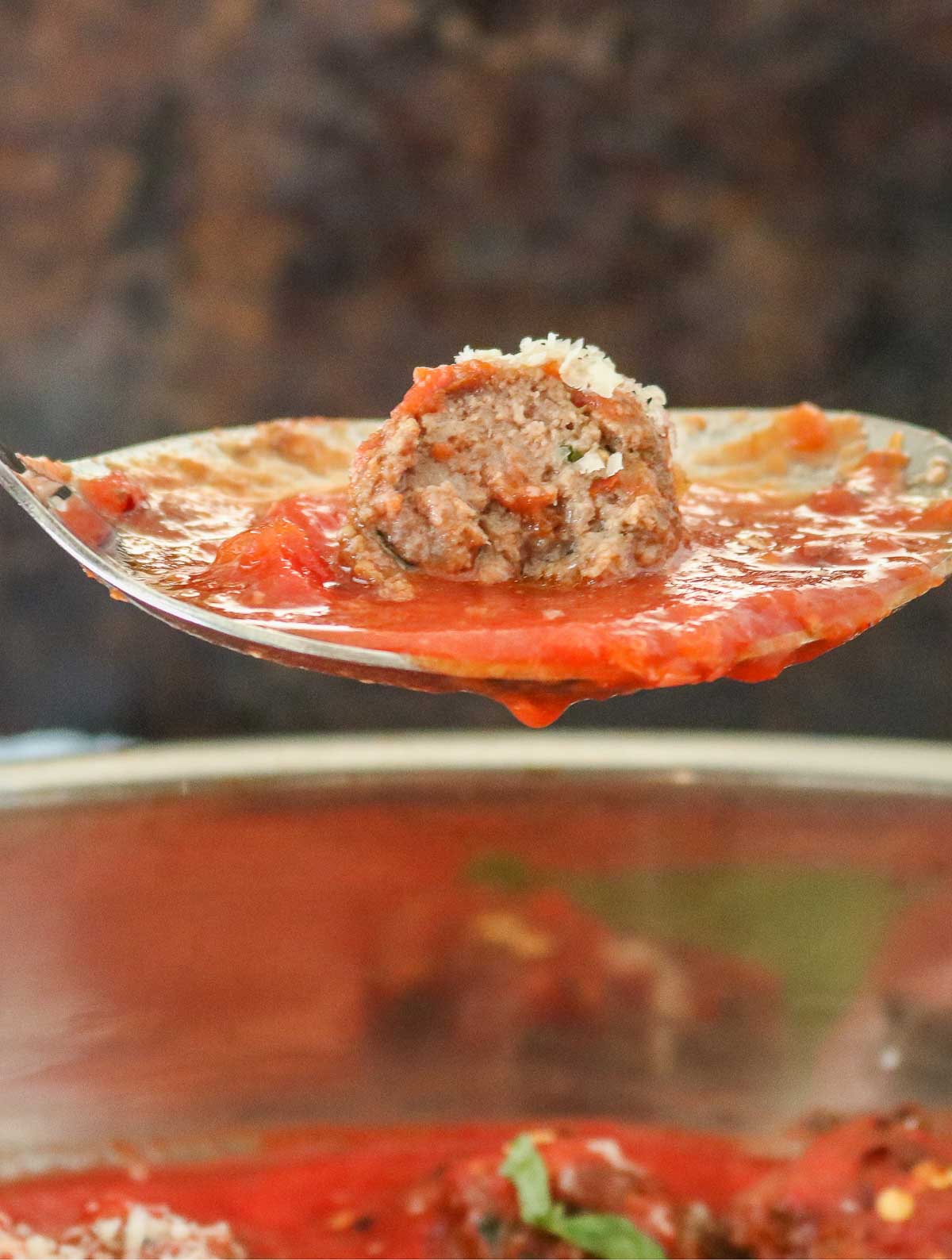 Homemade meatball and sauce on a serving spoon.