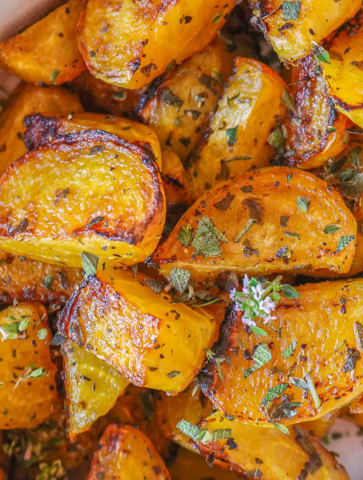 Close-up of roasted golden beets garnished with sage and thyme.