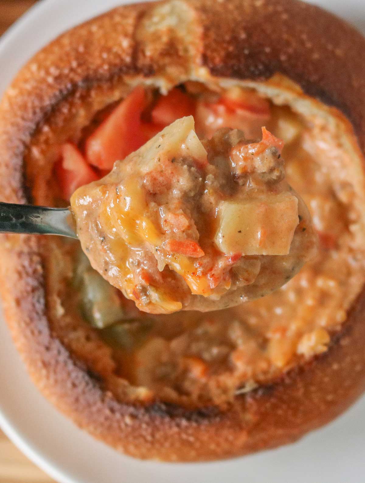 Spoonful of cheeseburger soup from a bread bowl.
