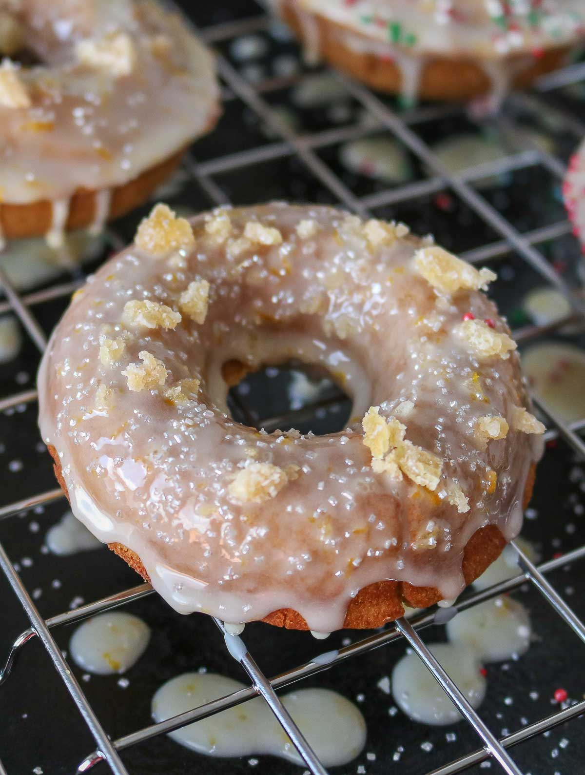 Glazed gingerbread donut on a cooling rack topped with sprinkles and candied ginger.