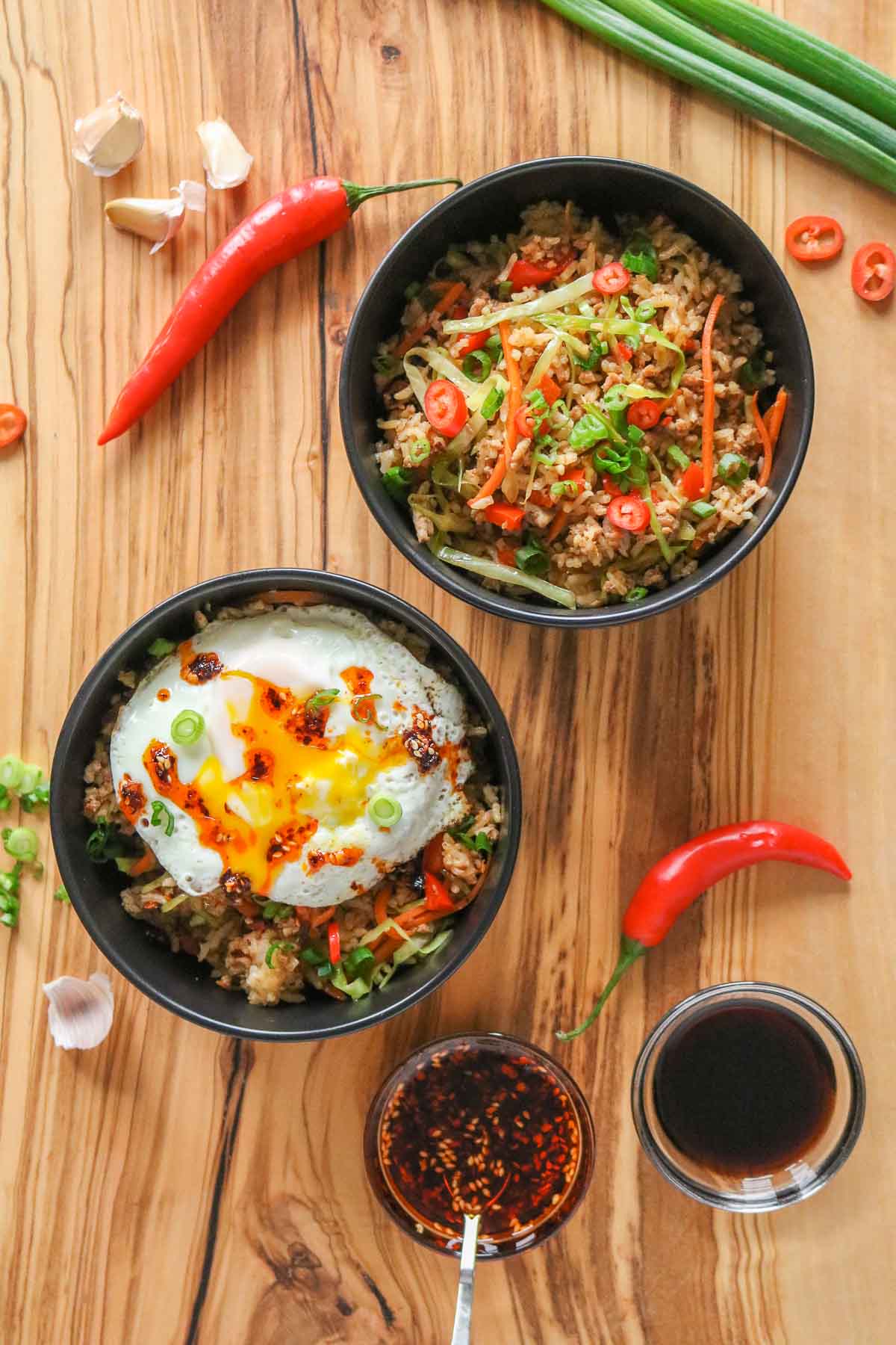 Two bowls of fried rice, one topped with an egg and one without.