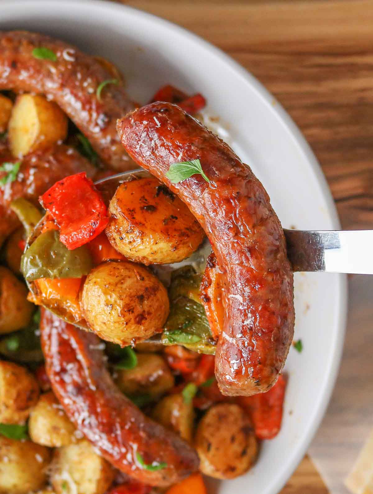 Sausage and veggies on a serving spoon.