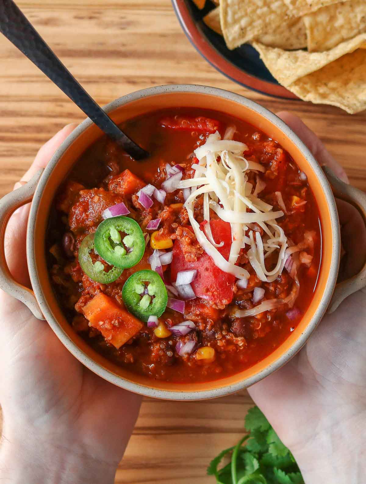 Two hands holding a bowl of chili.