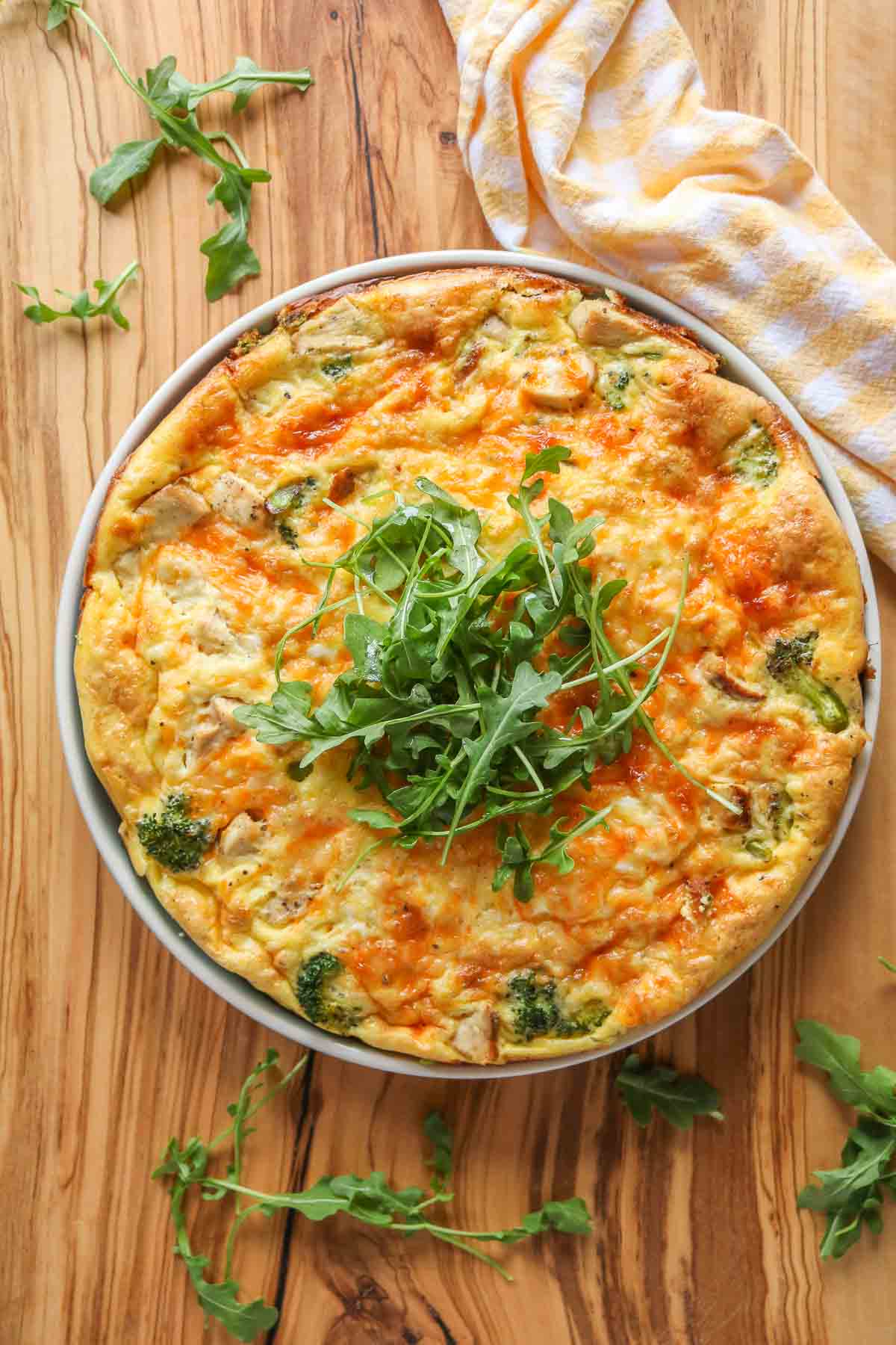 Broccoli chicken frittata on a plate topped with arugula.